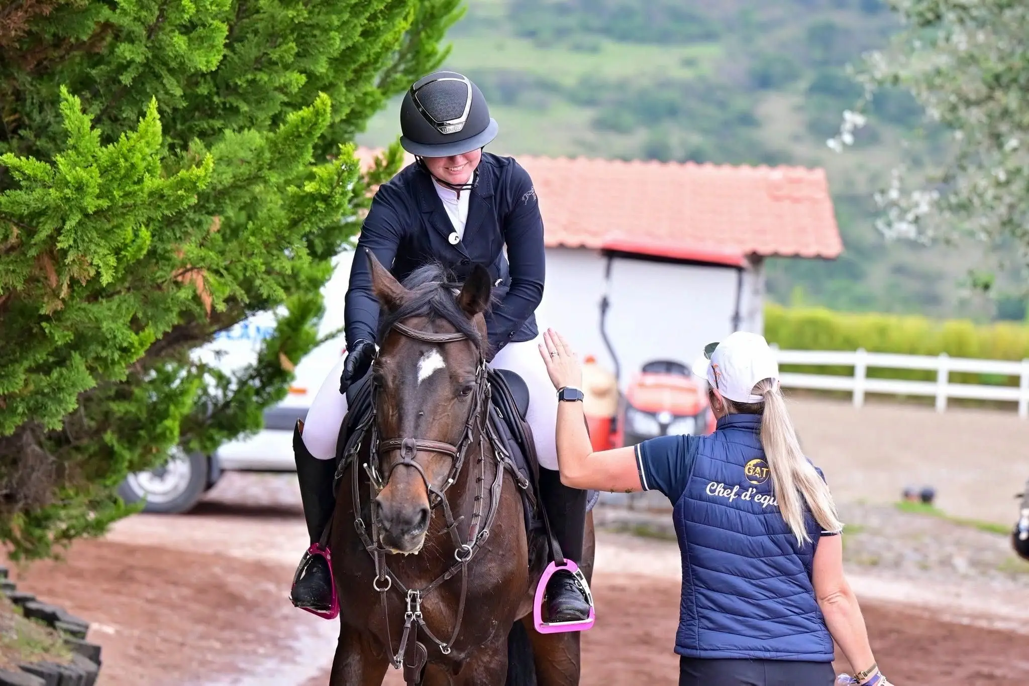 A Global Amateur Tour chef d'equipe reaching up to high five a rider still mounted after a round