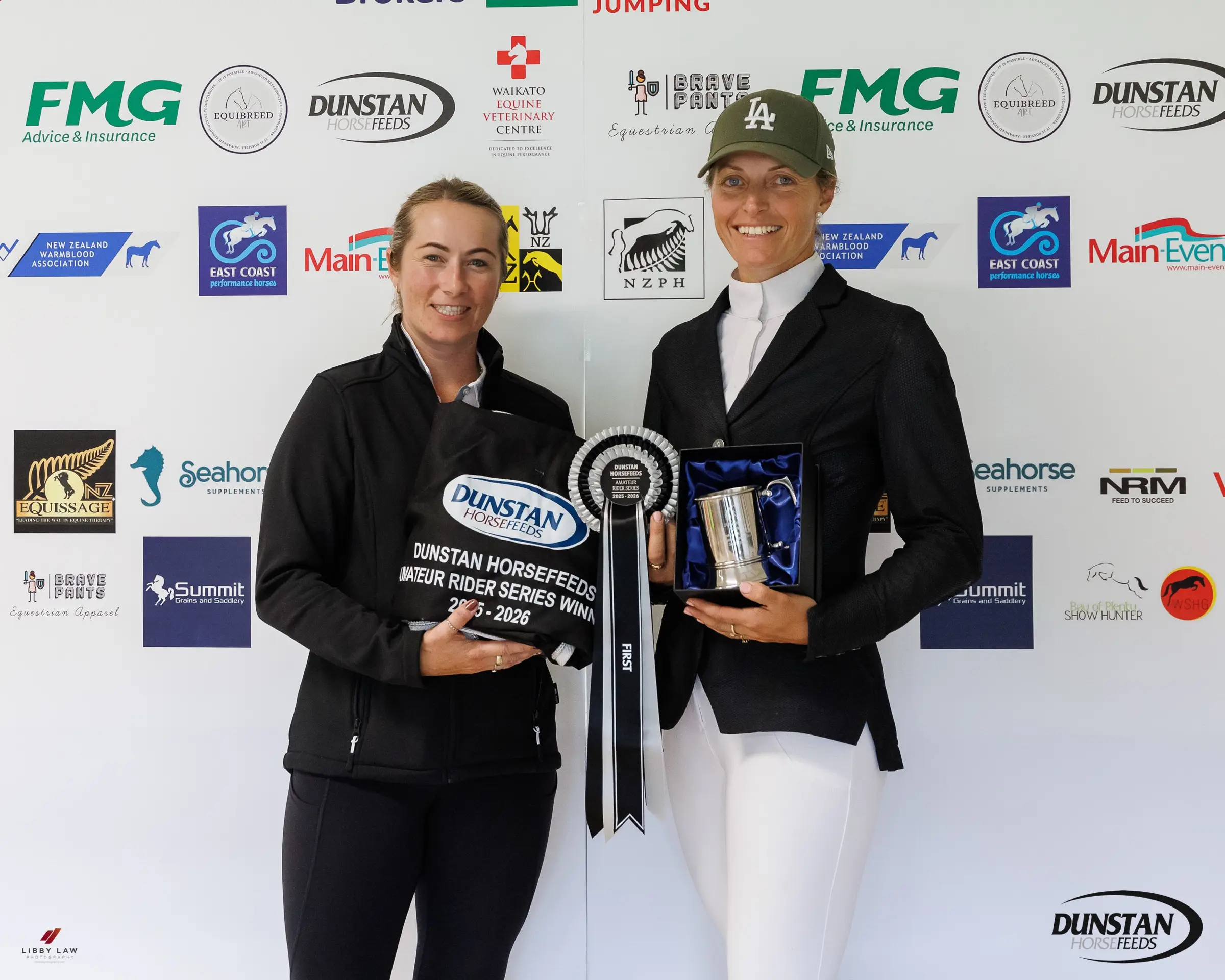 A rider receiving the Dunstan Horsefeeds Amateur Rider Series trophy and rosette in front of a sponsor backdrop