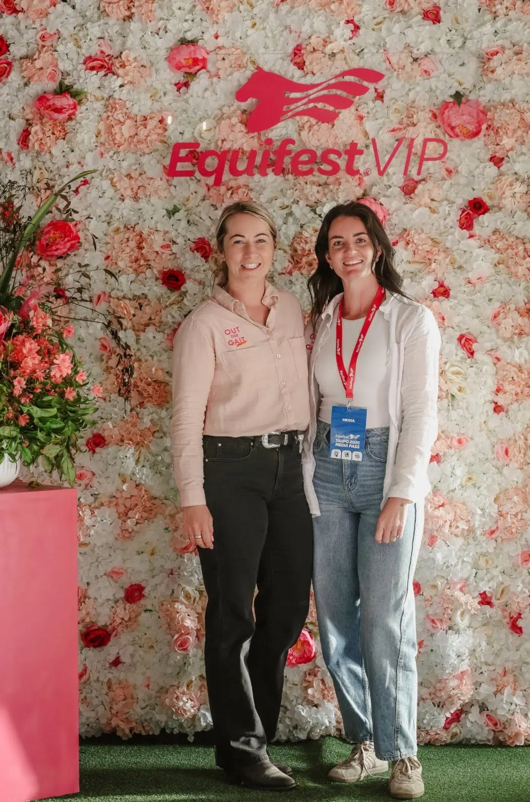 Paxton in an Out the Gait embroidered shirt with a colleague in front of the Equifest VIP flower wall