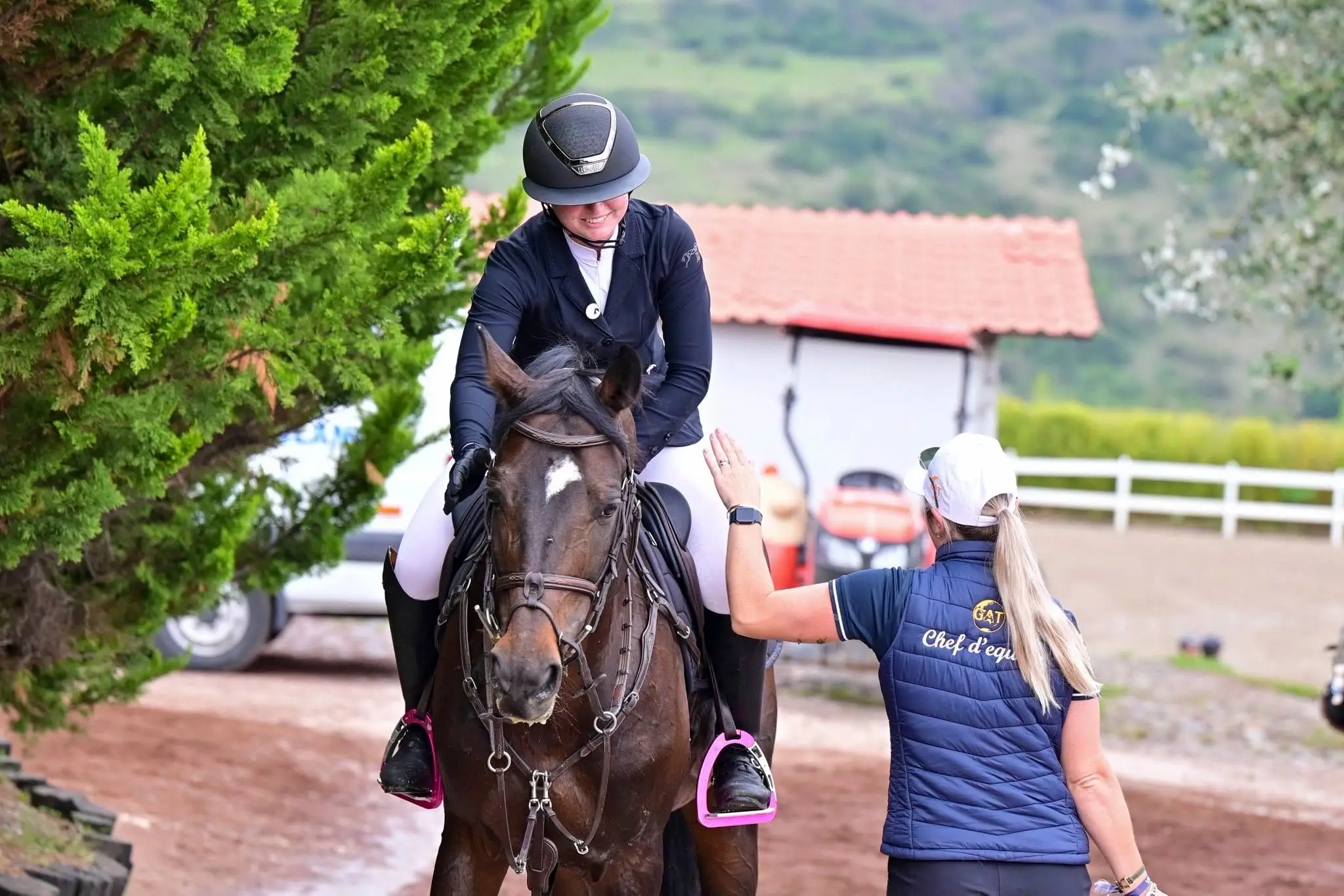 A Global Amateur Tour chef d'equipe reaching up to high five a rider still mounted after a round